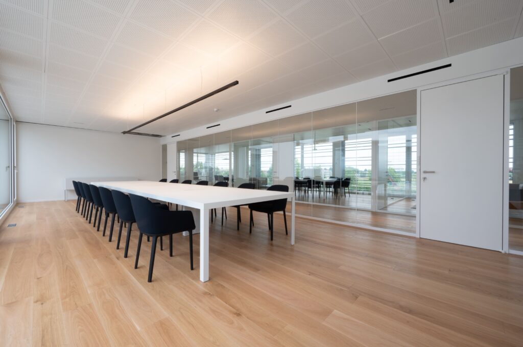 Sala riunioni Vermetal con tavolo centrale, vetrate e finiture contemporanee